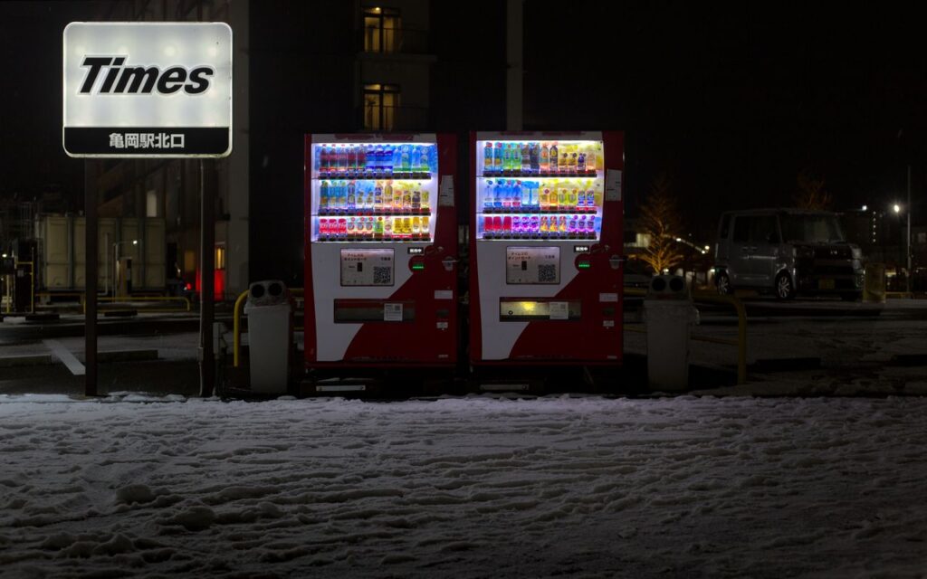 Illuminated vending machines in snowy Kameoka, Japan at night.