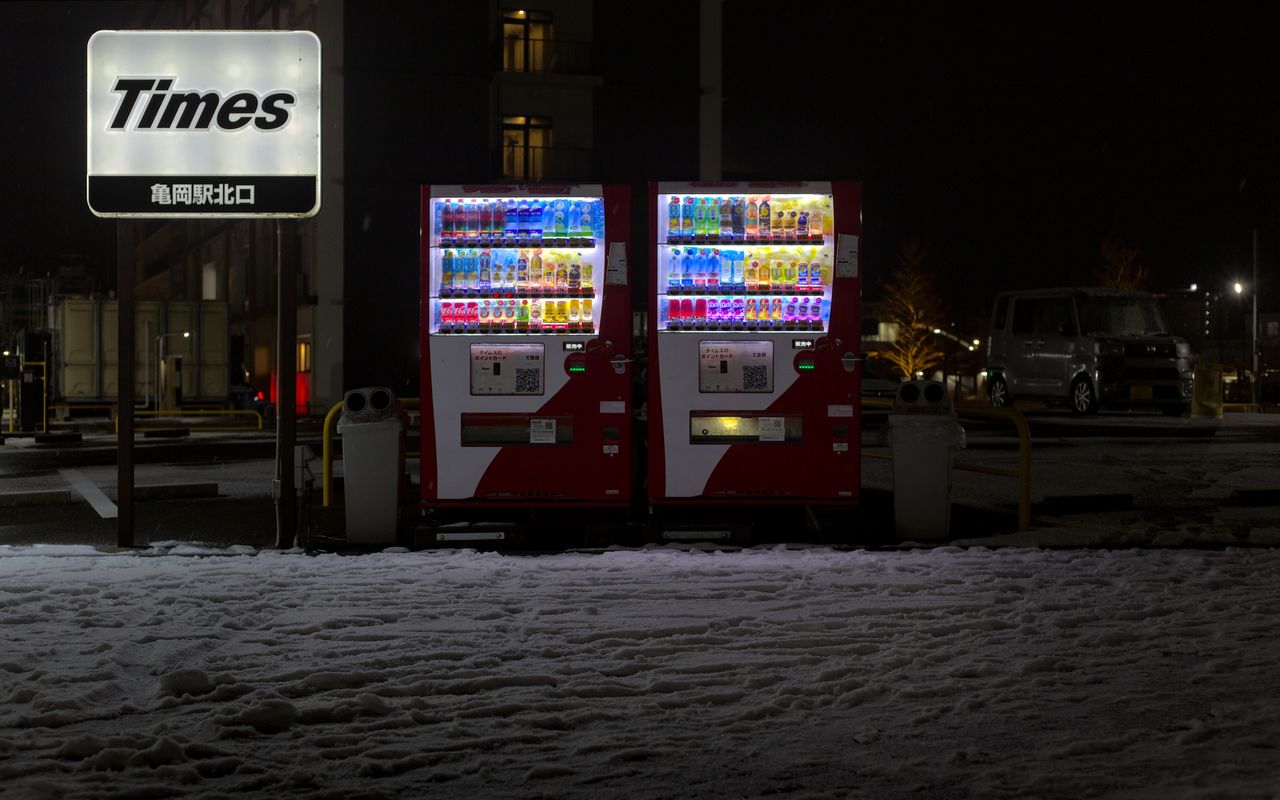 Illuminated vending machines in snowy Kameoka, Japan at night.